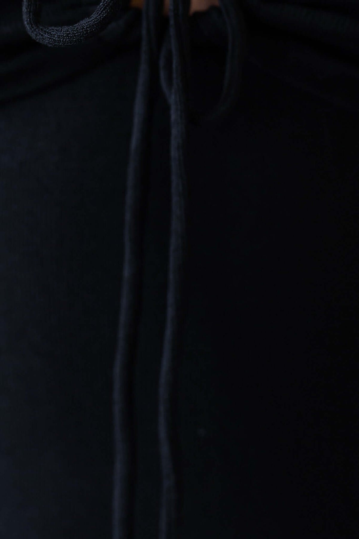 Close-up of the tie detail on the neckline of a black dress, showcasing its elegant design.