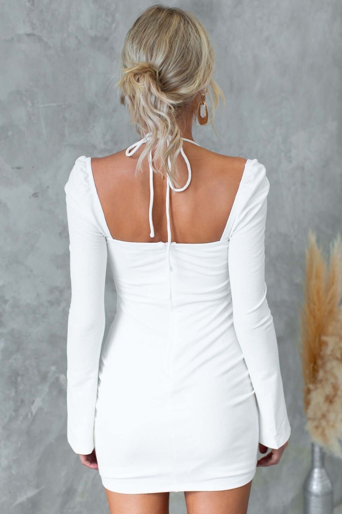 Back view of the Rehna Dress featuring tie detail, long sleeves, and a fitted silhouette in white.