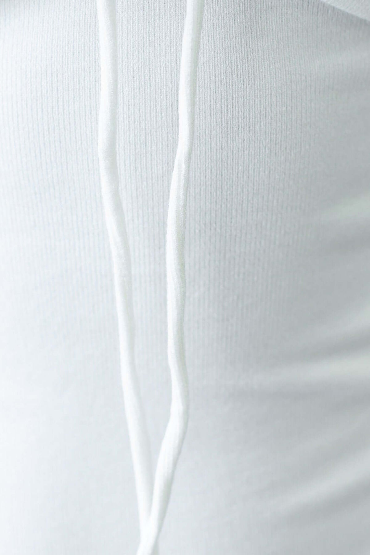 Close-up of a white dress with a tie detail at the neckline, highlighting the fabric texture and design.