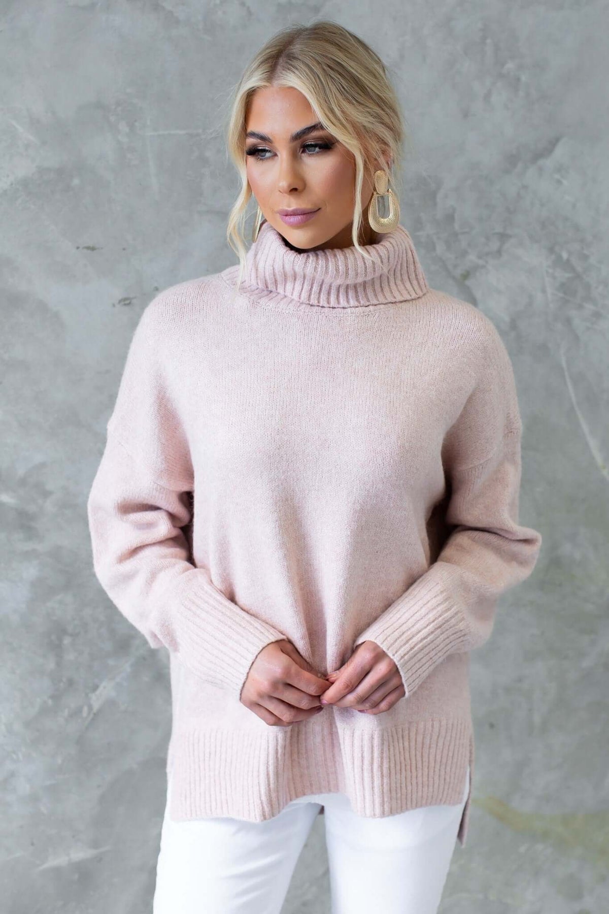 Model wearing a pink ribbed knit Orion Jumper with turtle neckline and side splits, styled casually.