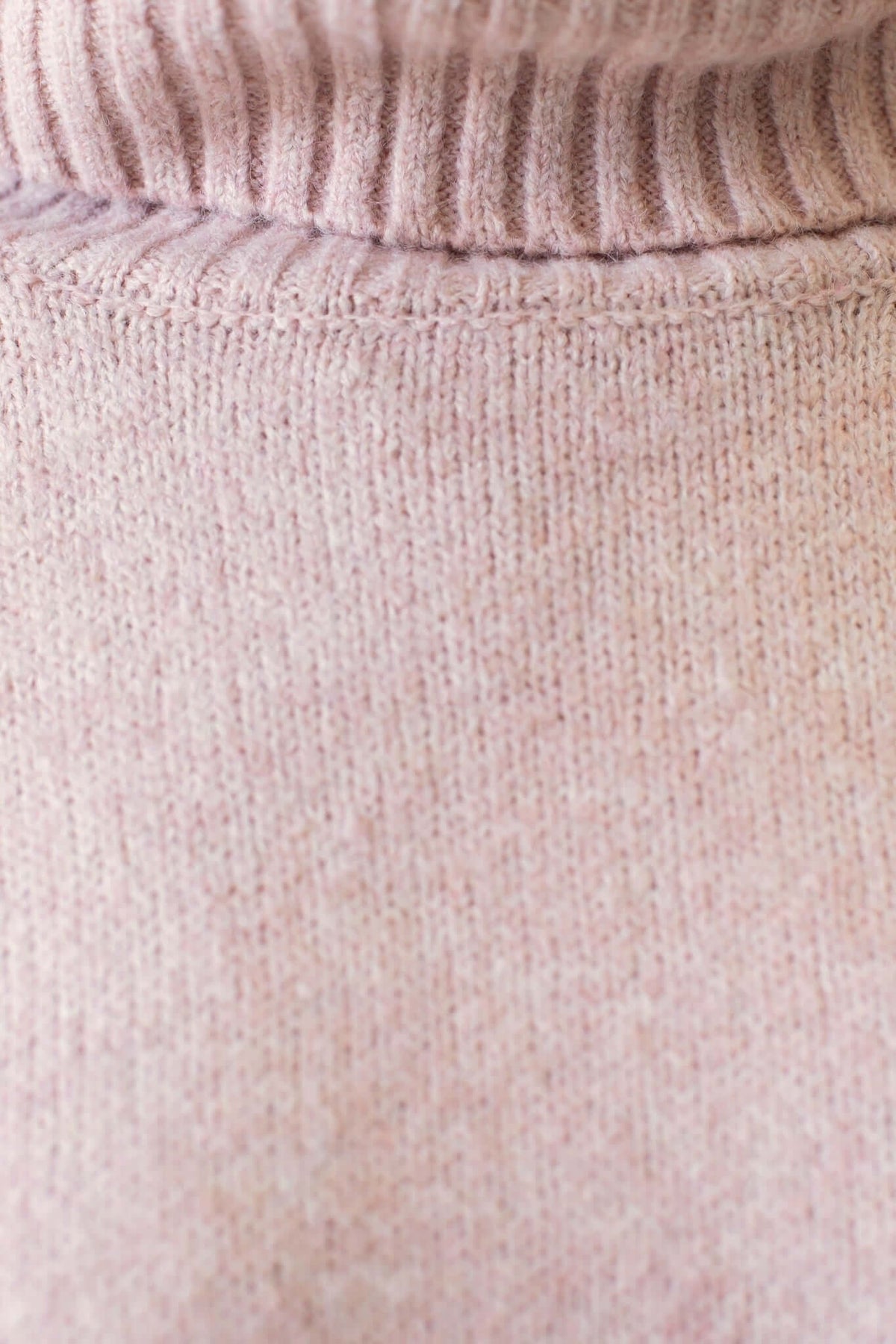 Close-up of a soft pink ribbed knit jumper fabric with a turtle neckline texture.