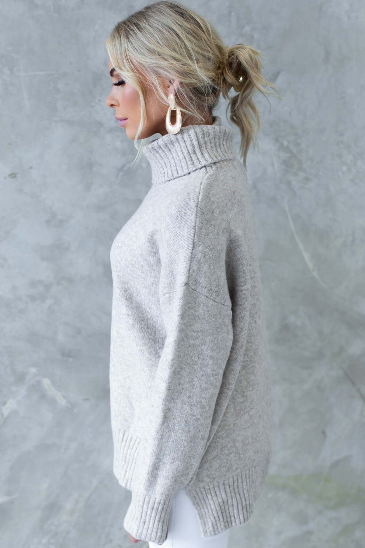 Side view of a woman wearing a stylish ribbed knit grey Orion jumper with a turtle neckline and relaxed fit.
