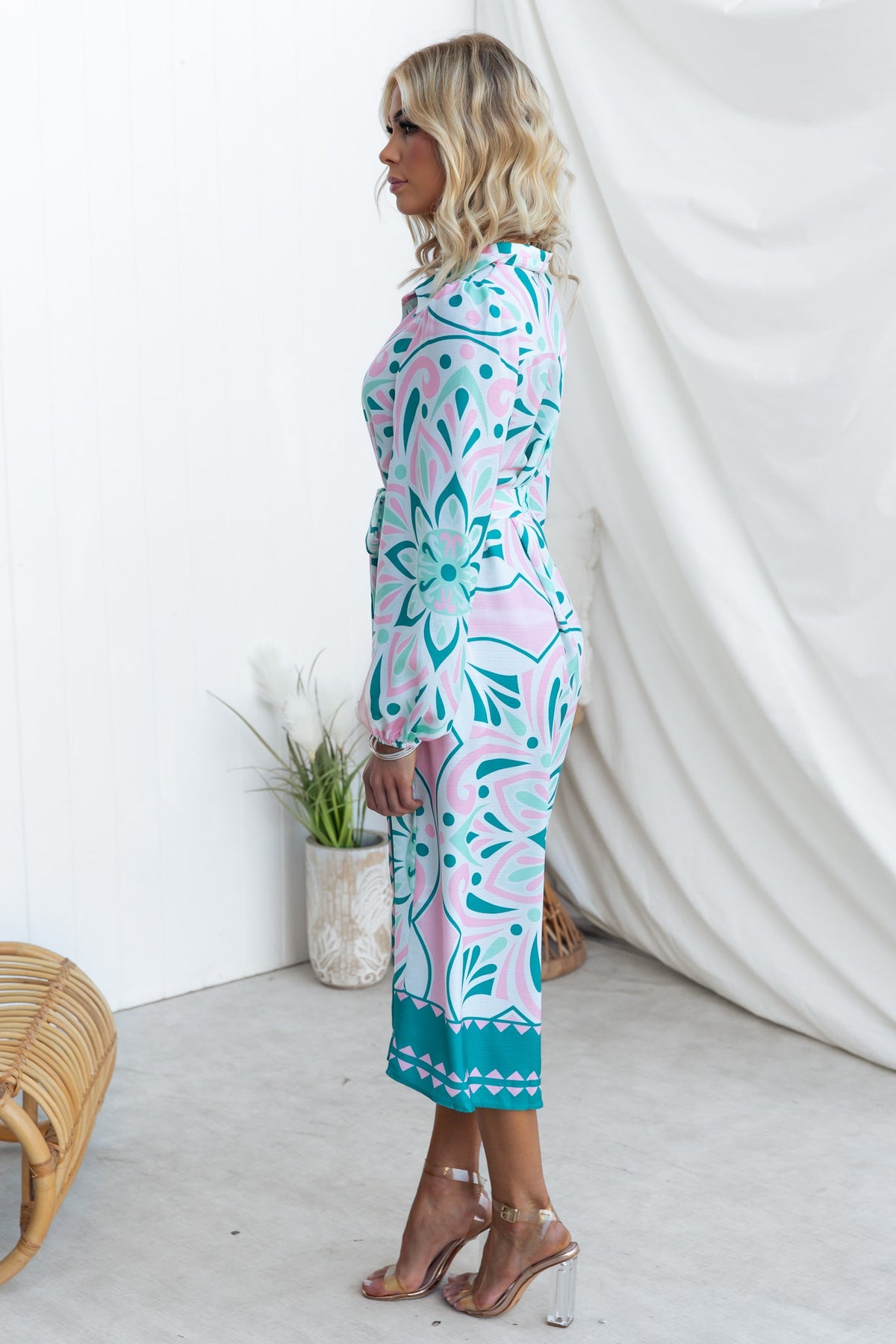 Side view of a woman in a colorful Faenza Midi Dress with floral patterns and a fitted silhouette.