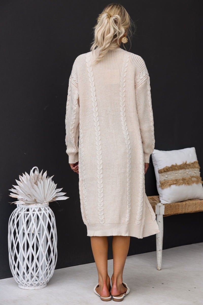Back view of a Dwyn Cable Knit Cardigan in cream, showcasing its longline fit and textured detail.