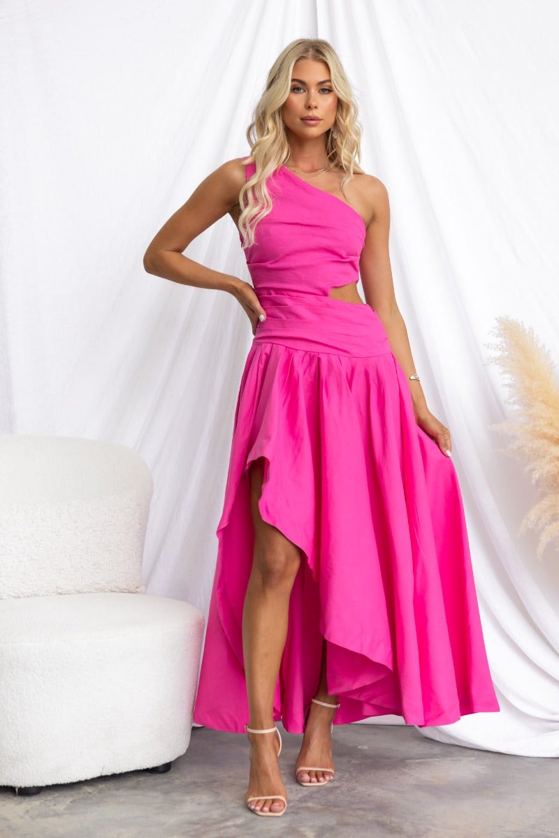Bright pink Horizons Maxi Dress with one-shoulder neckline and asymmetrical hemline, styled on a model.