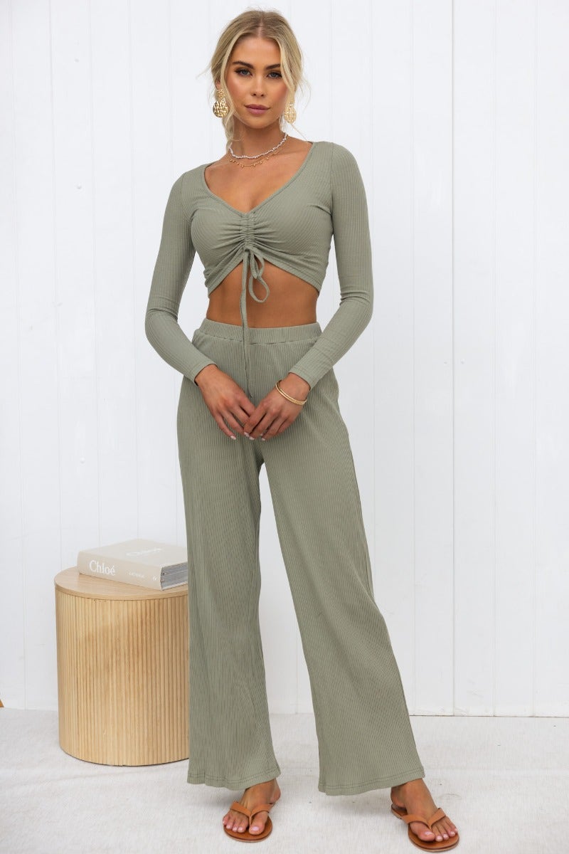 Model wearing Smitten Top in olive green with adjustable ruching and matching pants, styled on a minimalist background.