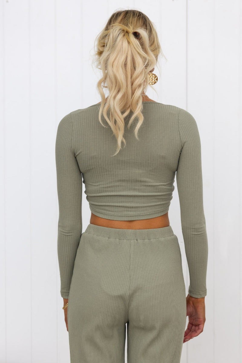 Back view of a woman wearing a ribbed V-neck Smitten Top in olive green, showcasing adjustable ruching at the bust.