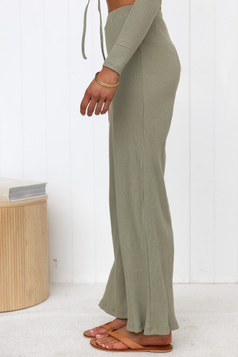 Side view of Smitten Pants in ribbed knit, featuring wide legs and an elastic waistband, styled with sandals.
