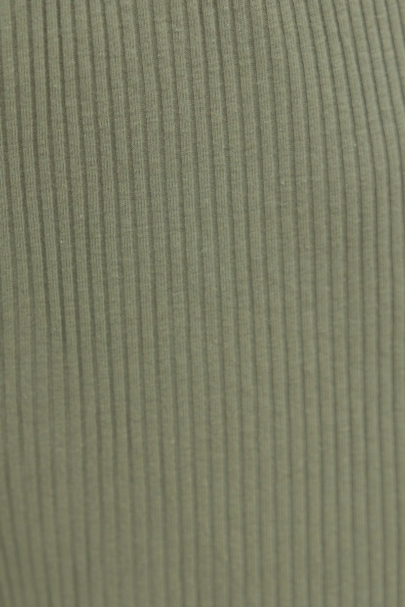 Close-up of ribbed knit fabric in soft green, showcasing texture and stretch for a stylish top.