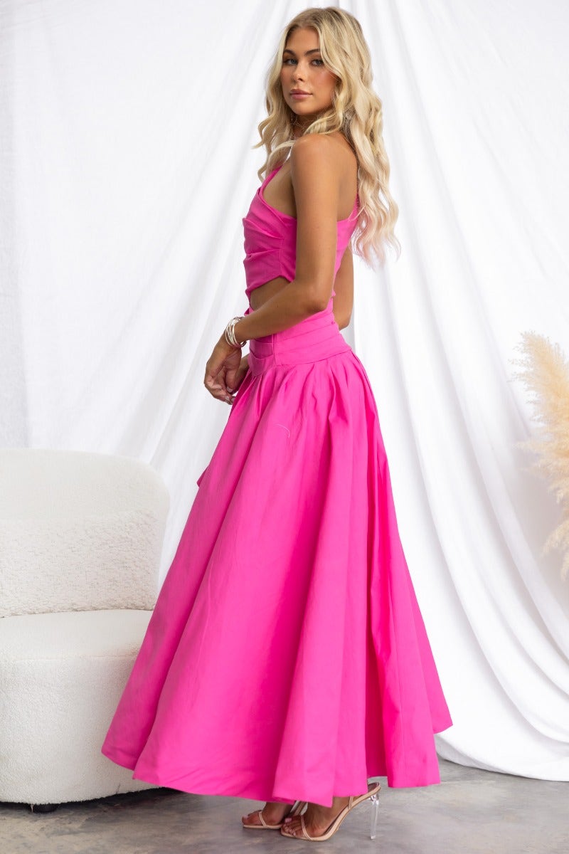 Model wearing a vibrant pink Horizons Maxi Dress featuring a one-shoulder neckline and asymmetrical hemline.