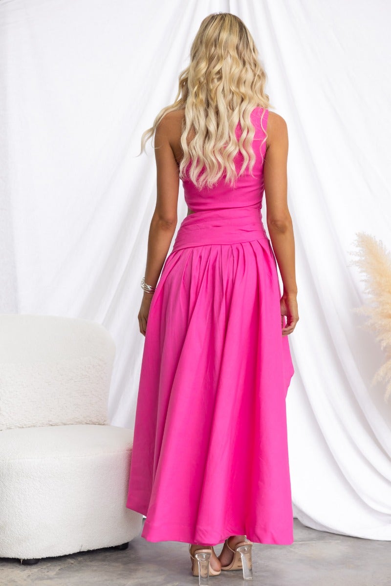 Back view of Horizons Maxi Dress in vibrant pink, showcasing its flowing design and one-shoulder neckline.