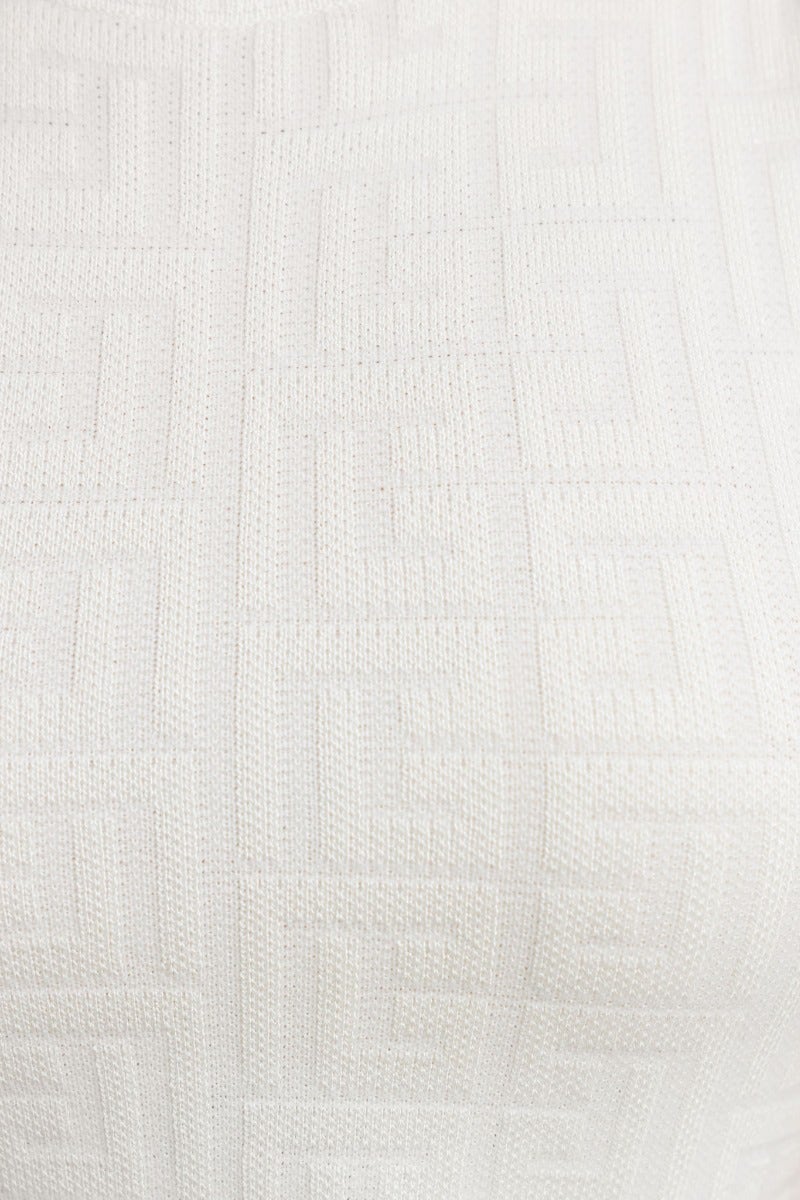 Close-up of embossed white fabric featuring a textured pattern, perfect for stylish garments like dresses.