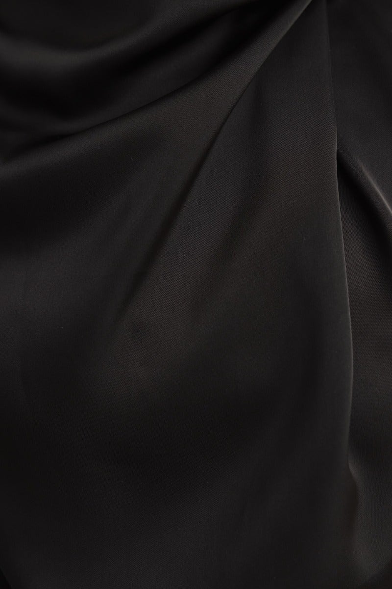 Close-up of black satin fabric, showcasing its smooth texture and rich color, ideal for a stylish top.
