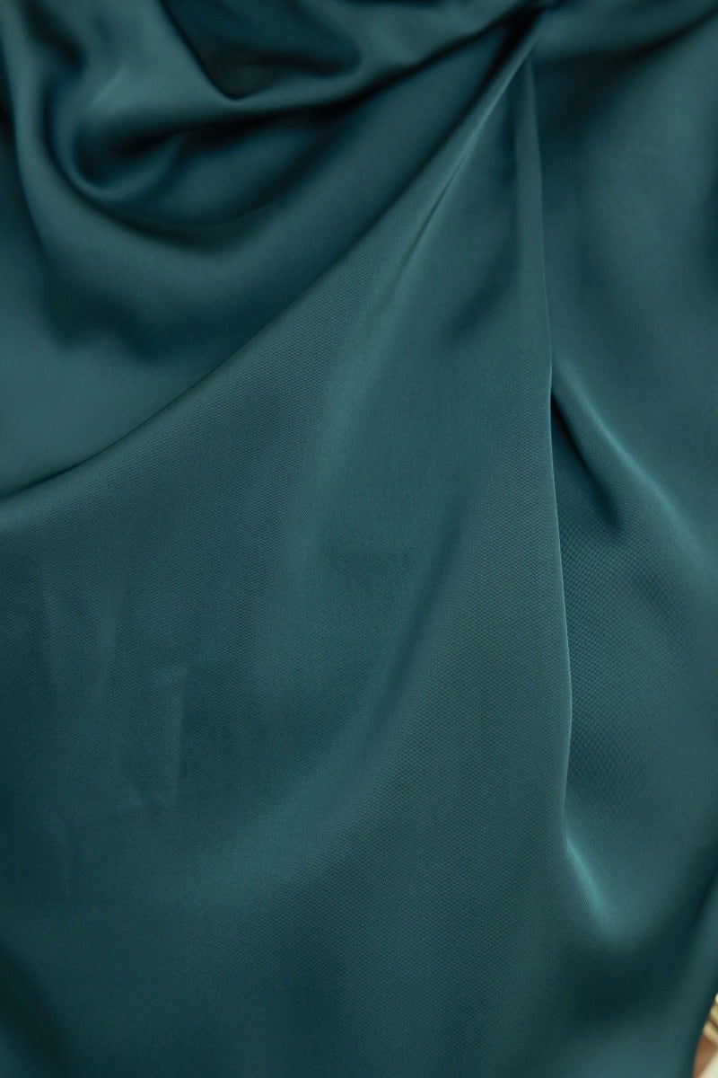 Close-up of lush teal satin fabric, showcasing its smooth texture and elegant drape for fashion design.