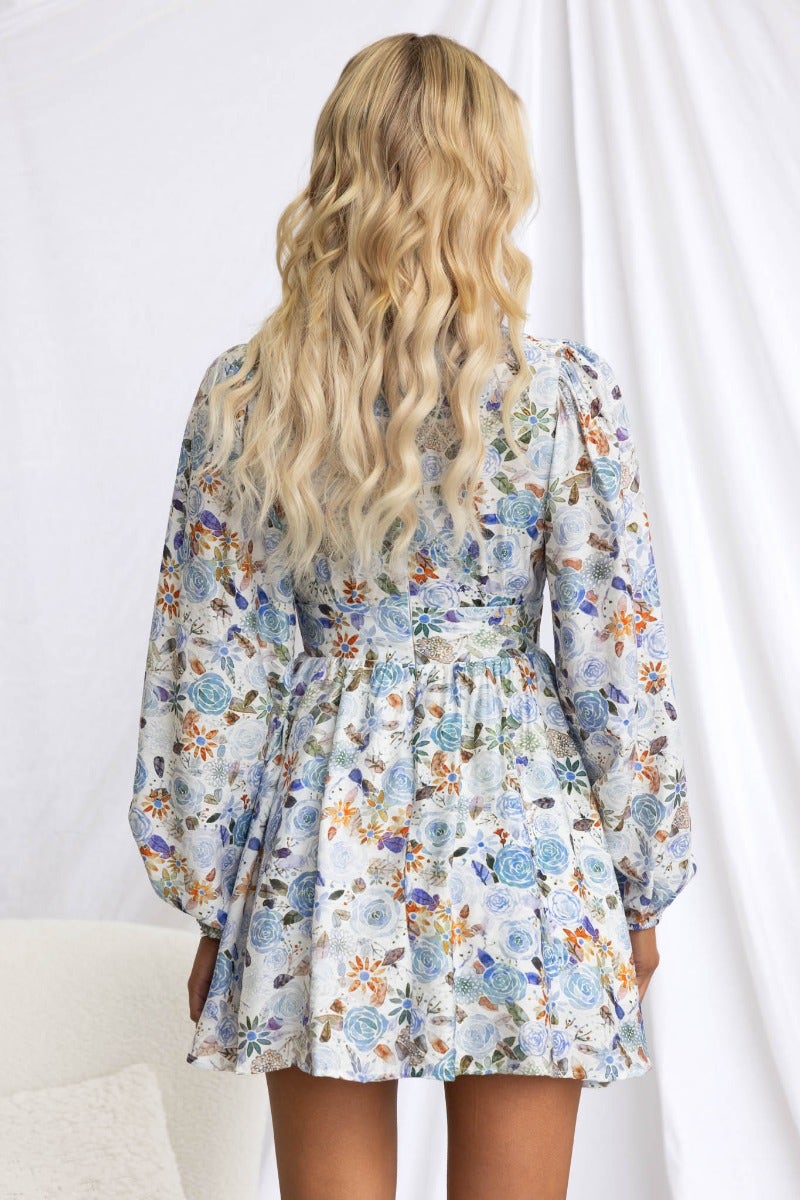 Back view of a floral print dress with V-neckline and puff sleeves, showcasing the elegant design and playful silhouette.