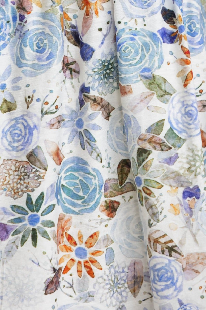 Detailed floral pattern on fawn midi dress featuring blue roses and colorful botanical designs.