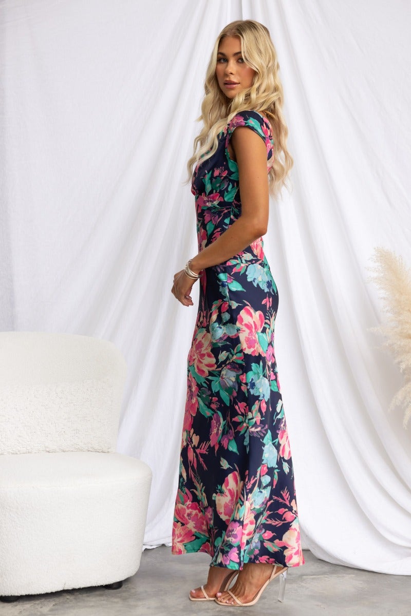 Model in a navy floral print maxi dress with cap sleeves and a twist detail, showcasing a stylish look.