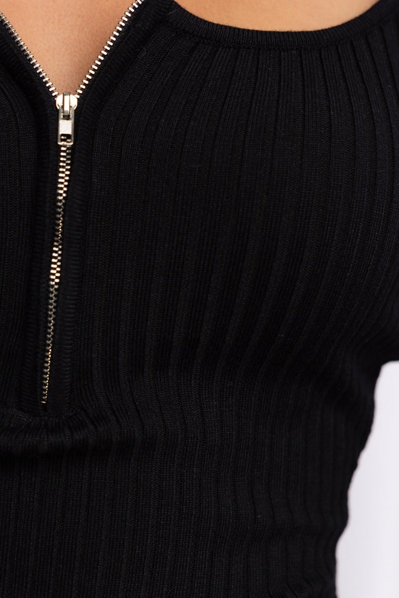 Close-up of black ribbed bodysuit featuring a zip-up bust and scoop neckline.