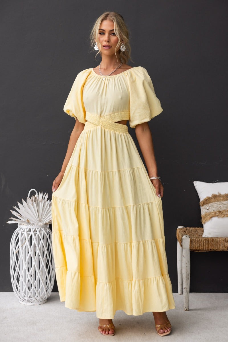 Elegant yellow cotton maxi dress with off-shoulder neckline and cut-out waist detail, perfect for summer occasions.