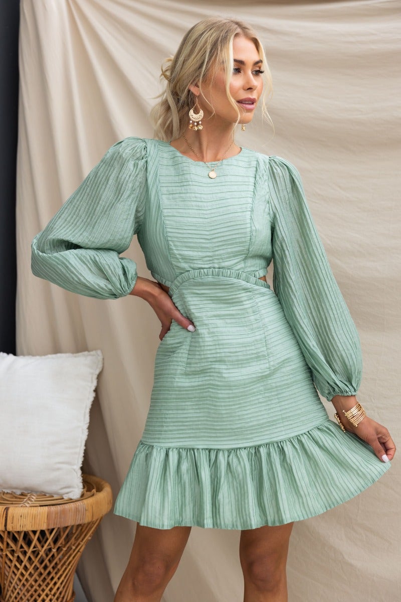 Tovia Dress in textured green fabric, featuring a round neckline, puff sleeves, cut-out waist, and ruffled hem.