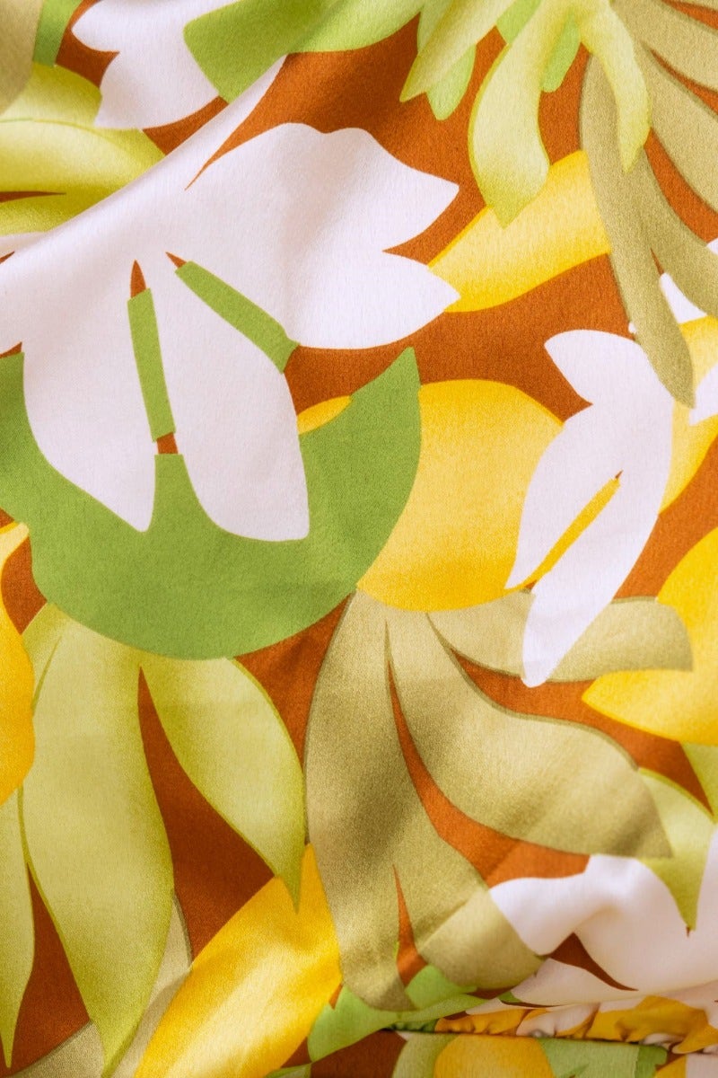 Vibrant floral pattern in yellow and green on satin fabric, perfect for summer dresses and stylish outfits.