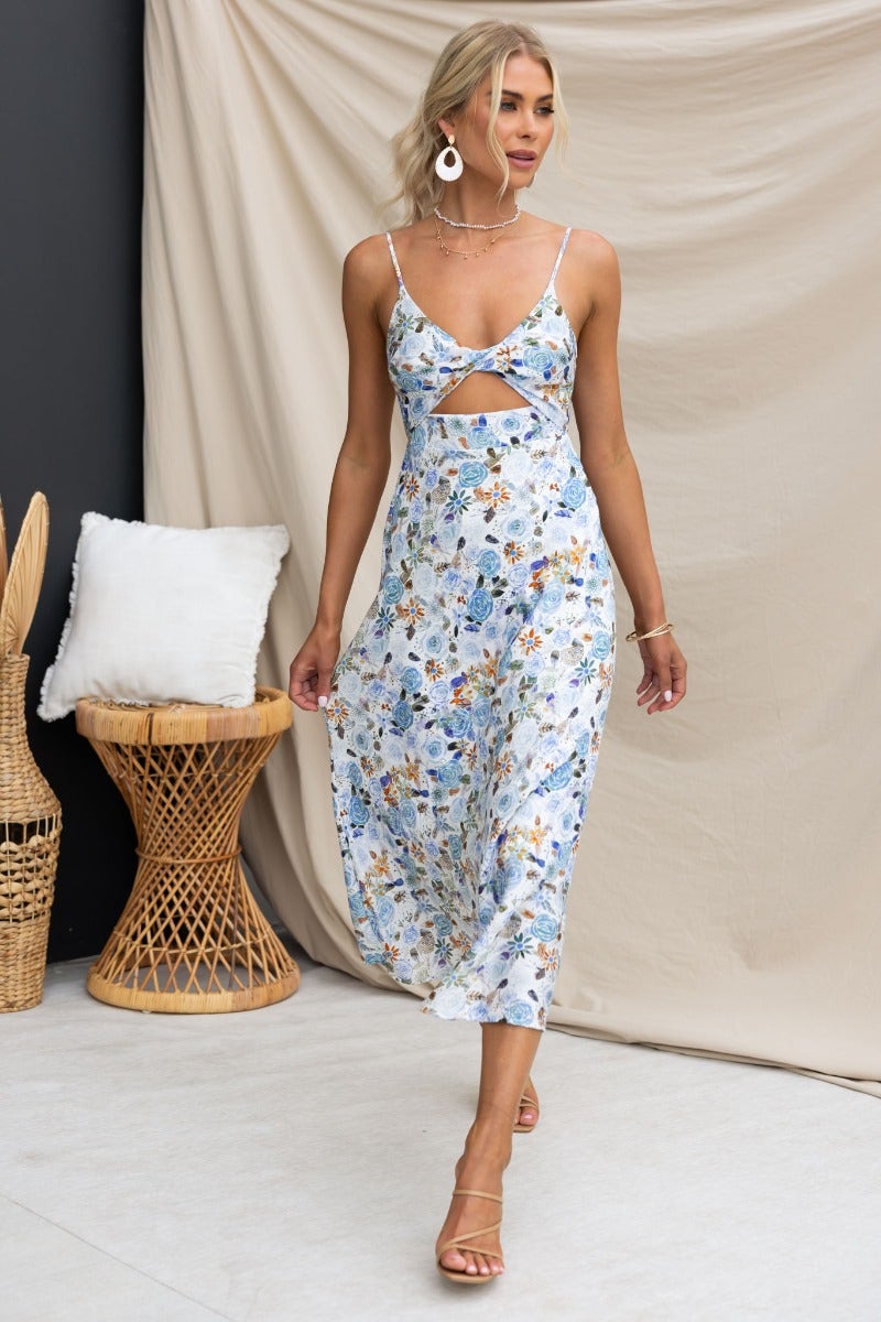Fawn midi dress with floral print, adjustable straps, and twist detail on a model walking against a neutral backdrop.