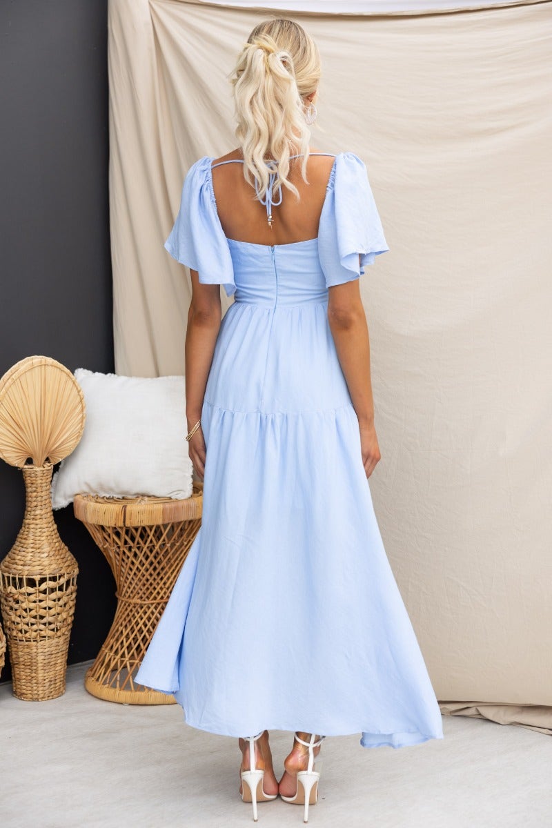 Back view of Hanni Maxi Dress in light blue, featuring elastic sleeves and tie detail, perfect for summer occasions.