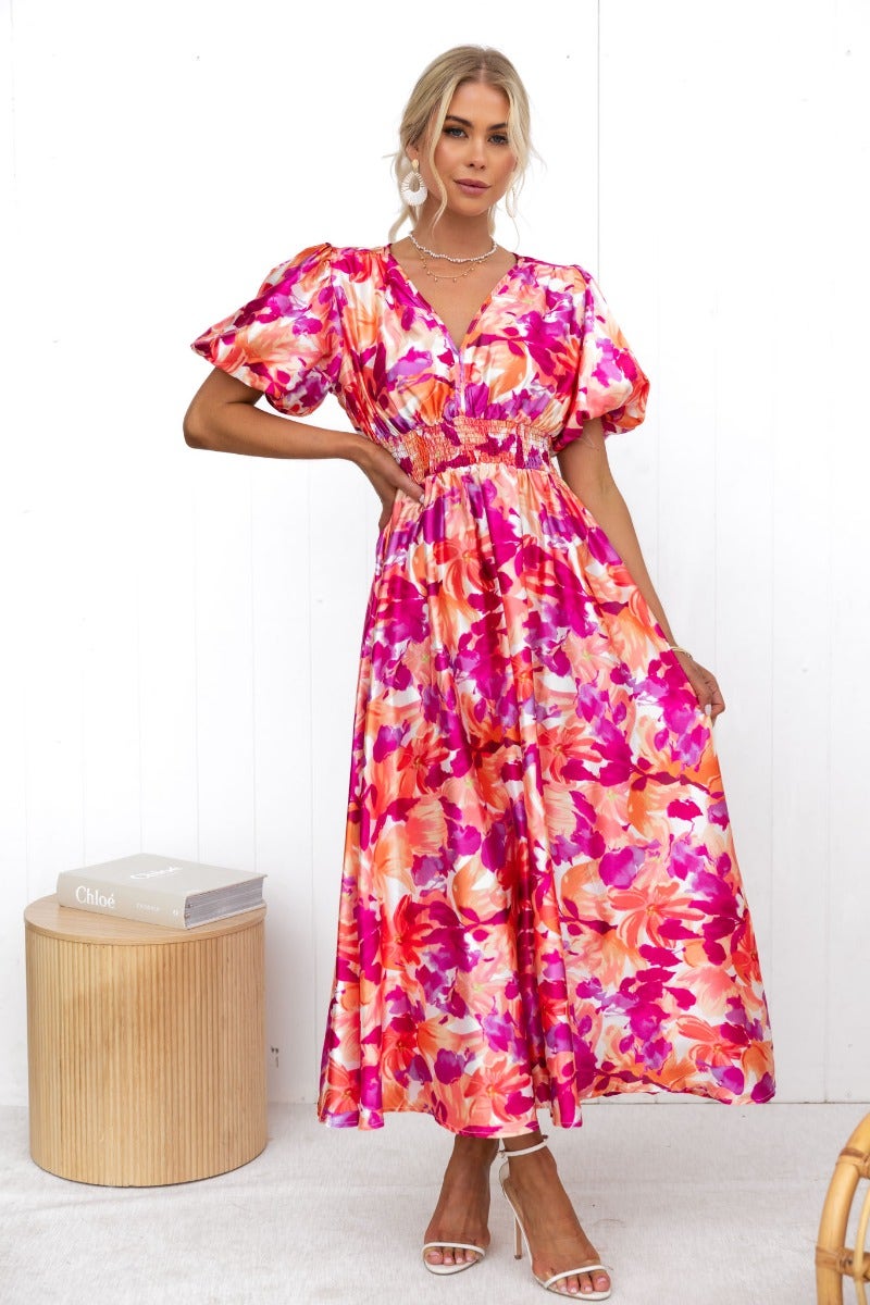 Model wearing a Blazing Maxi Dress featuring vibrant floral prints and V-neckline with elastic at sleeves and waistband.