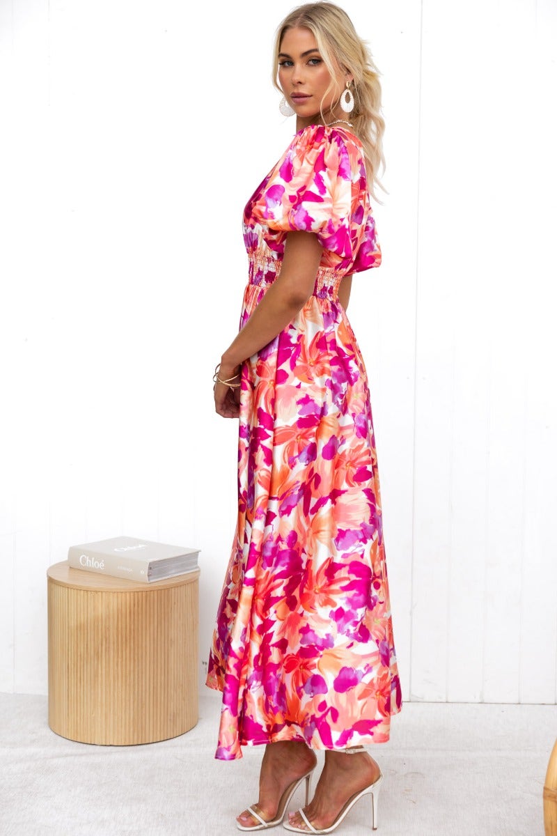 Model wearing a floral print Blazing Maxi Dress with a V-neckline and elastic cuffs, styled in a chic setting.