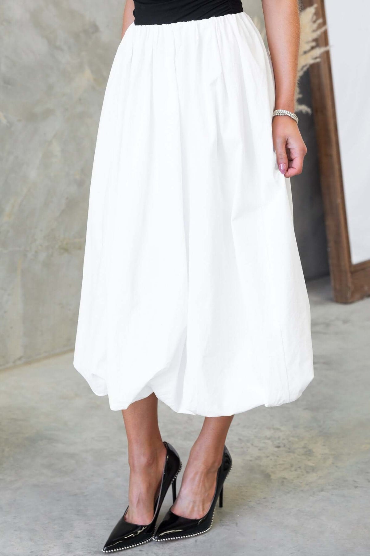 Model wearing a Cloud Nine Midi Skirt, featuring a mid-high waist, elastic waistband, and a flowy design in white.