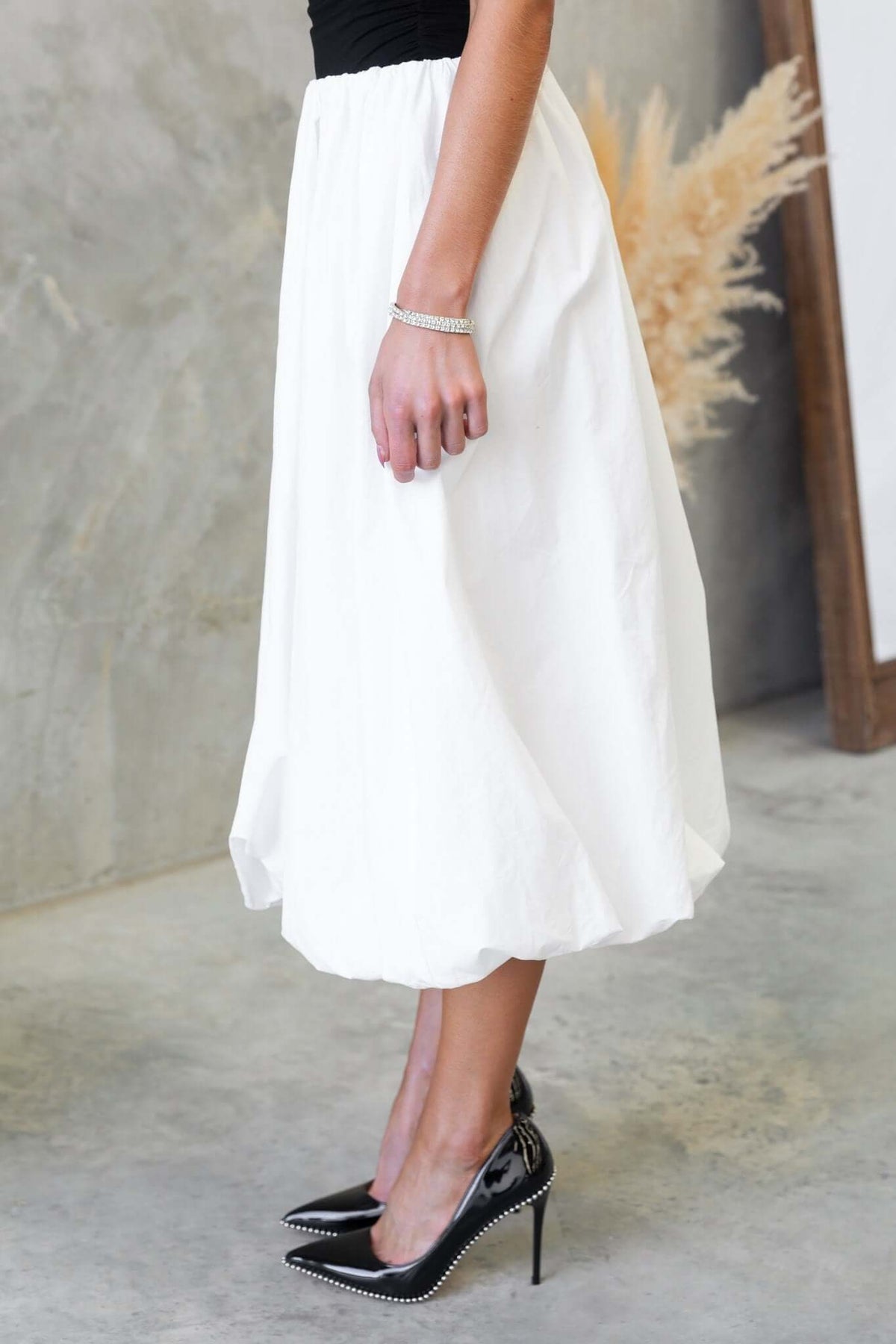 Cloud Nine Midi Skirt in white, featuring mid-high waist and elastic waistband, styled with black high heels.