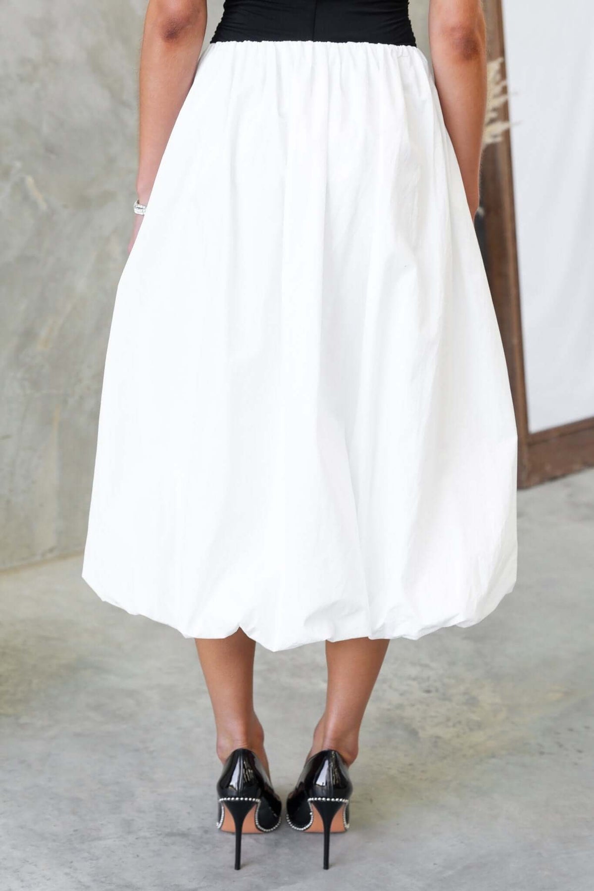 Cloud Nine Midi Skirt in white with mid-high waist and elastic waistband, styled with black high heels.