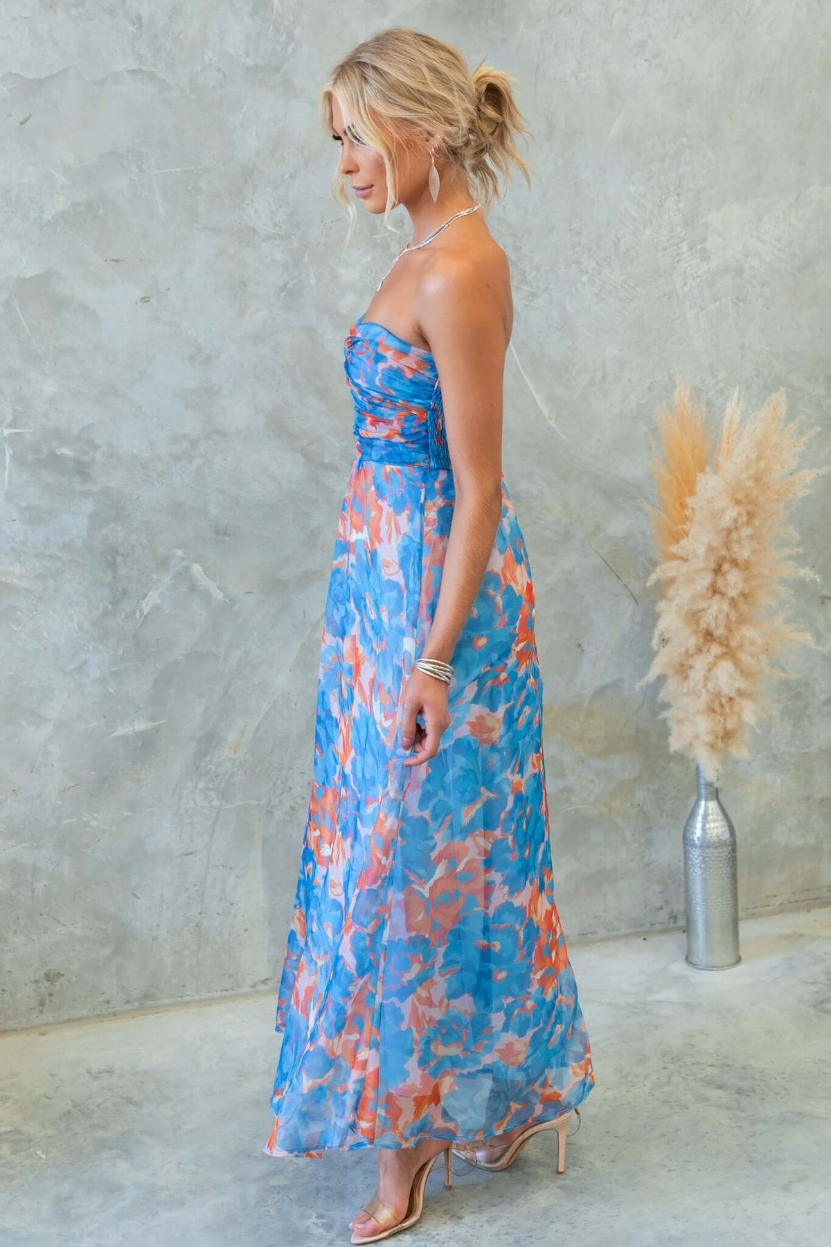Ivrea Midi Dress in blue floral print, strapless design with elastic back and invisible zip, styled with minimal accessories.
