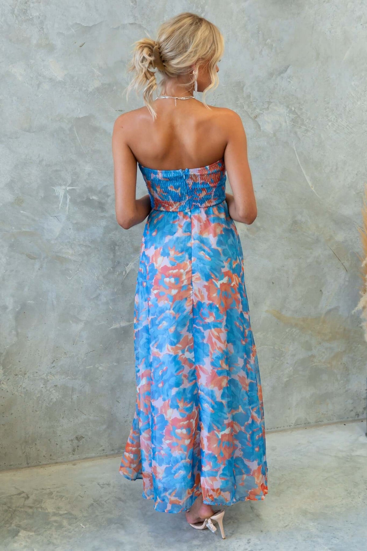 Back view of Ivrea Midi Dress in vibrant blue and orange floral print, showcasing strapless design and flowing skirt.