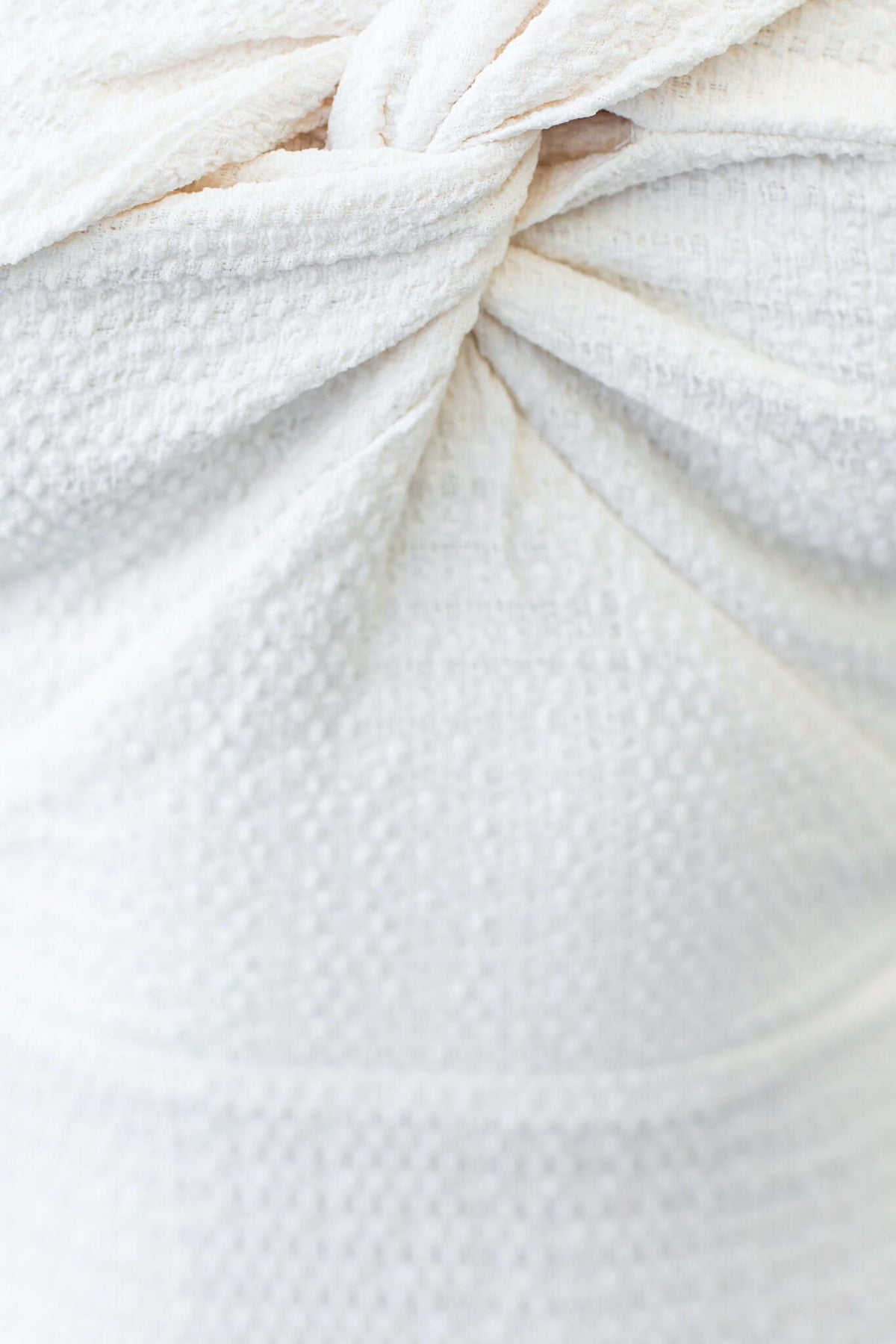 Close-up of the fabric detailing on a cream Fondi Midi Dress featuring a twisted texture and off-shoulder design.