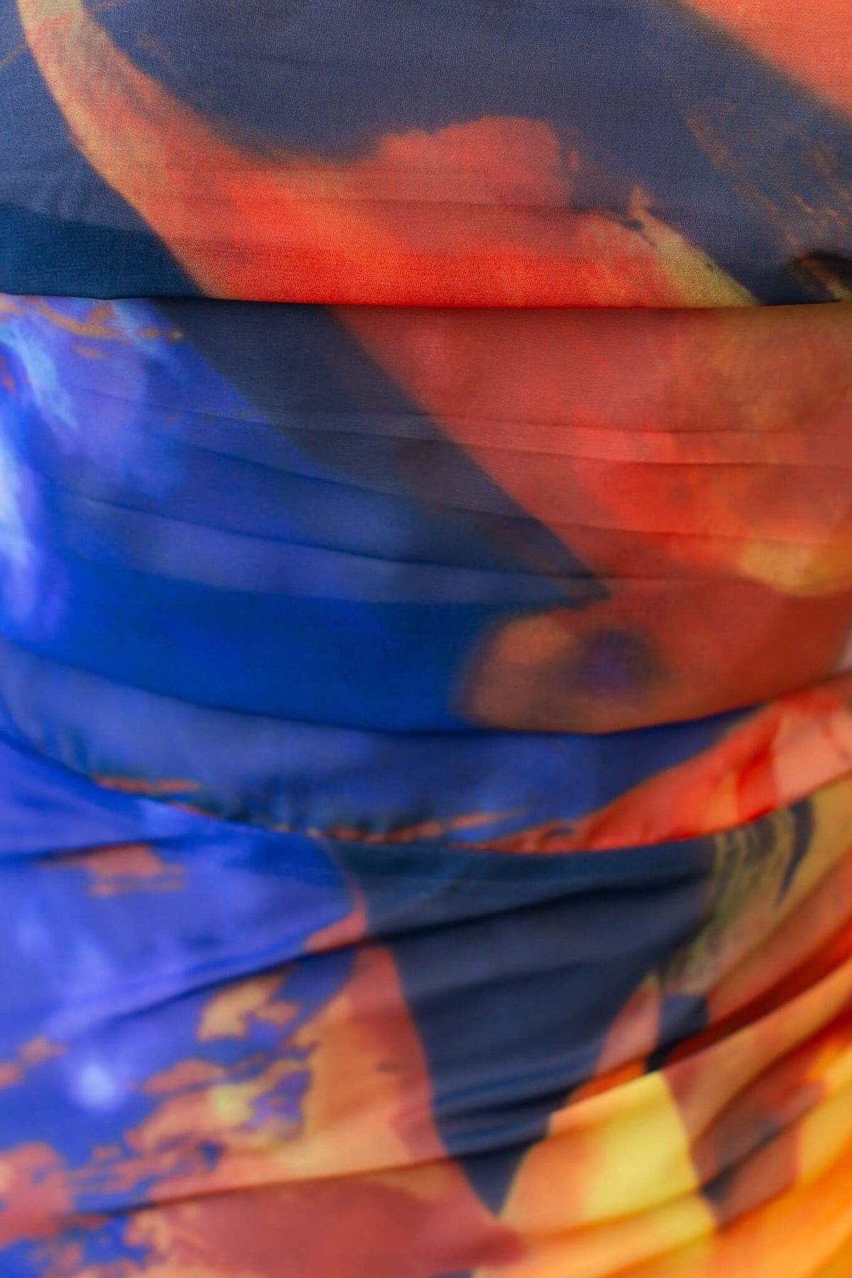 Close-up of the vibrant fabric of the Valentia Maxi Dress featuring swirling blue, orange, and red tones.