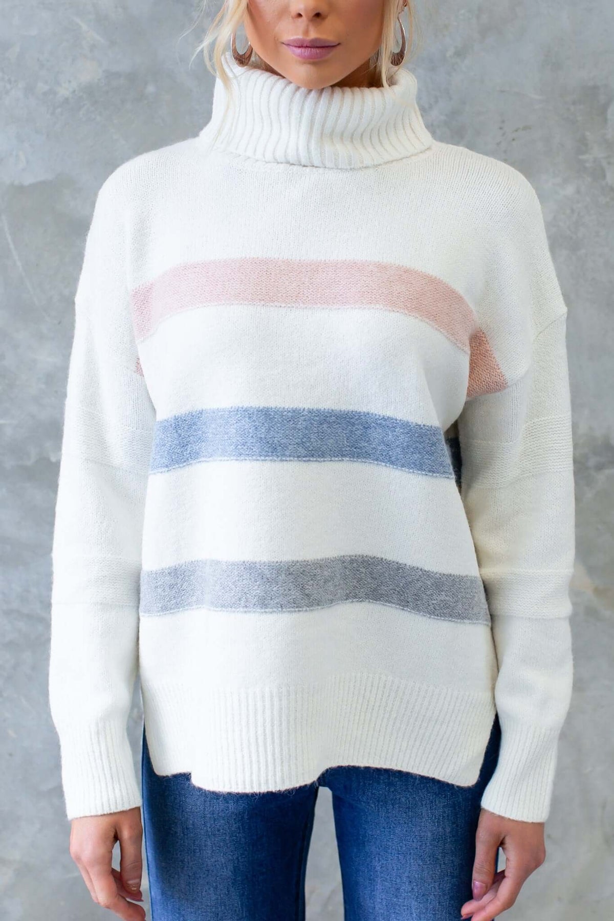 White striped Lovey Jumper with turtle neckline, featuring pastel pink and blue accents, styled with denim.