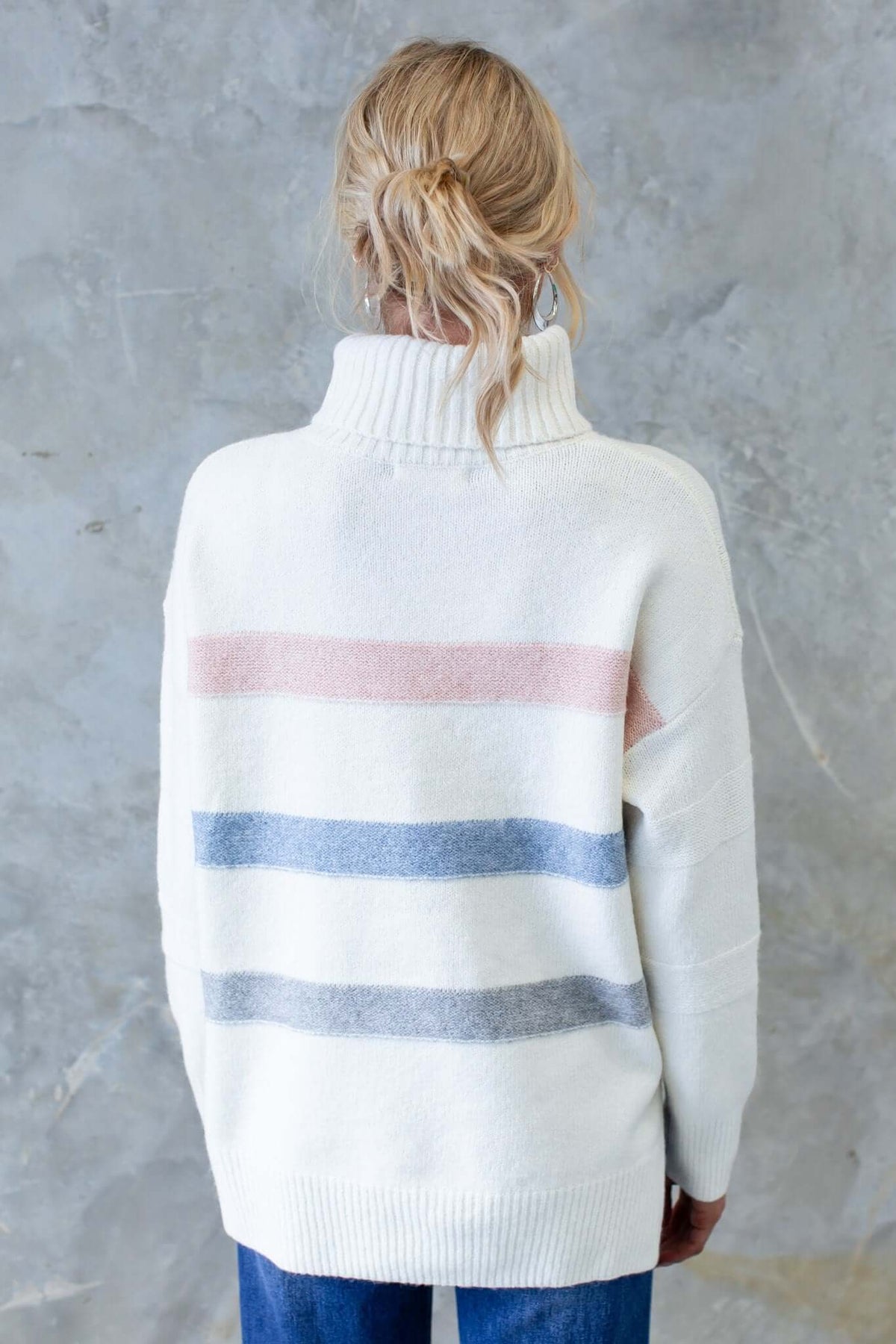 Back view of Lovey Jumper featuring a turtle neckline and striped pattern in soft pastels, worn by a model.