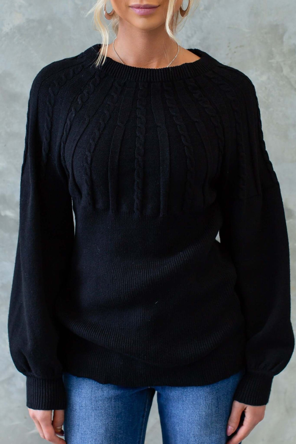 Model wearing a black cable knit Alma Jumper with a round neckline and relaxed fit.