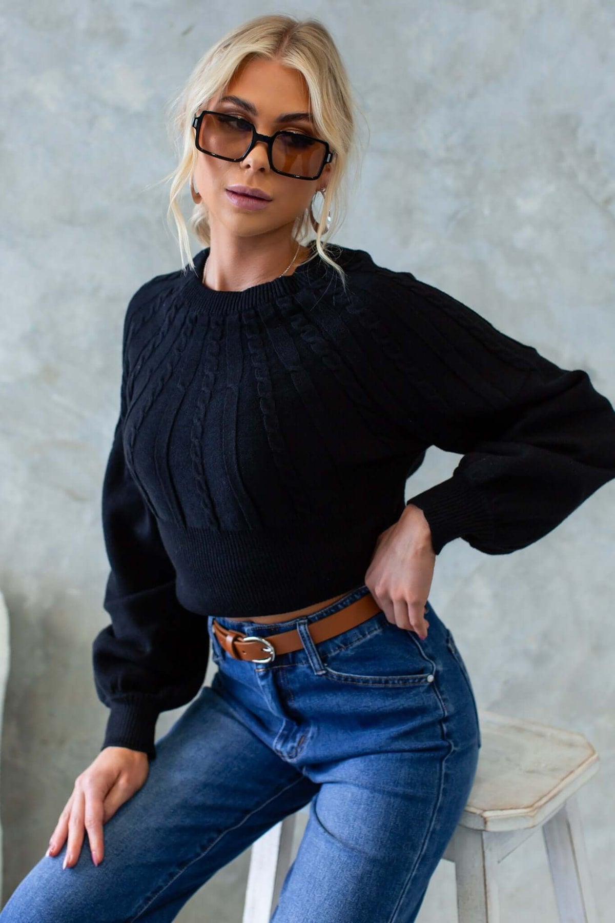 Model wearing the Alma Jumper, a black cable knit sweater with a round neckline and slightly relaxed fit.