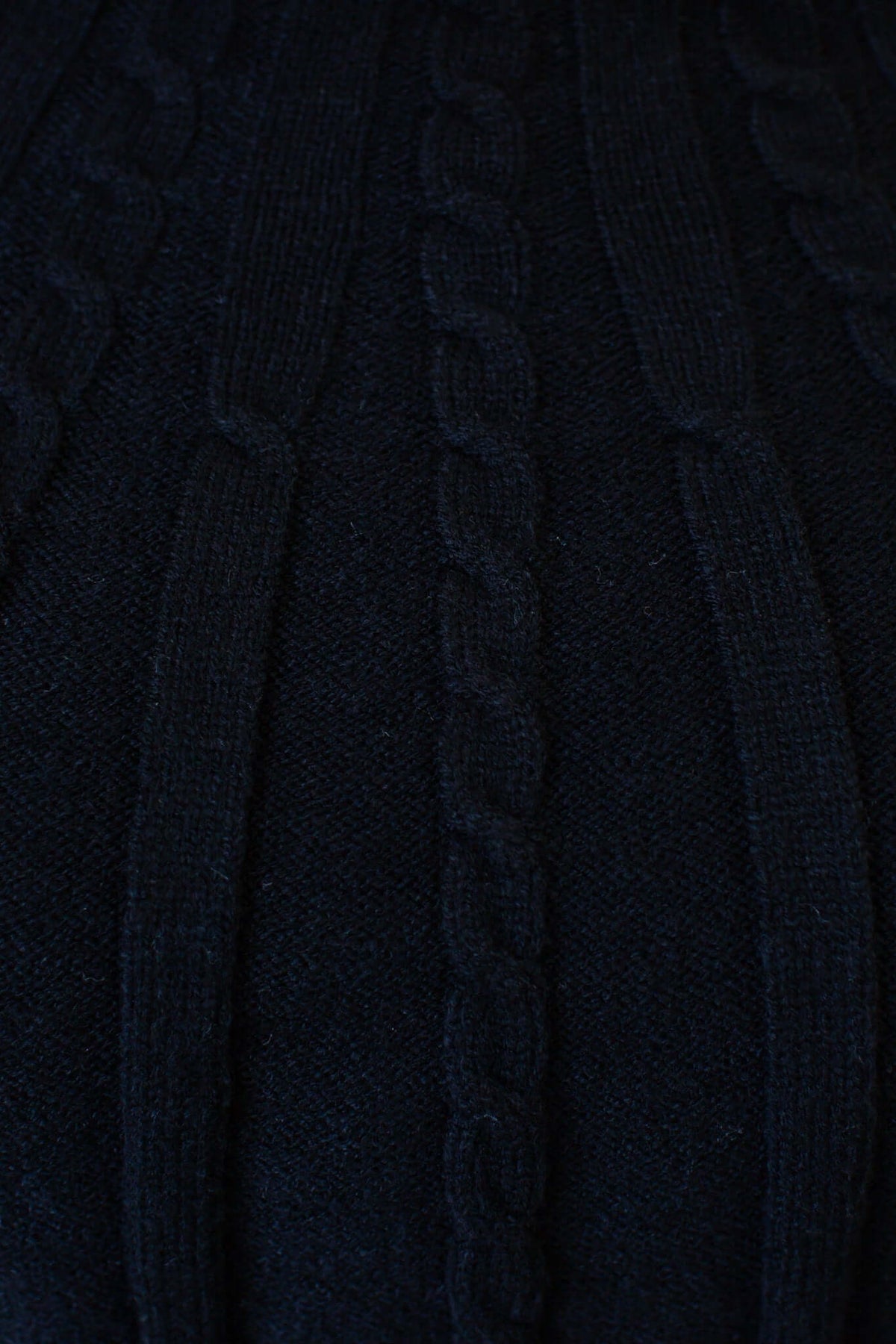 Close-up of the Alma Jumper featuring a black cable knit texture and a round neckline.