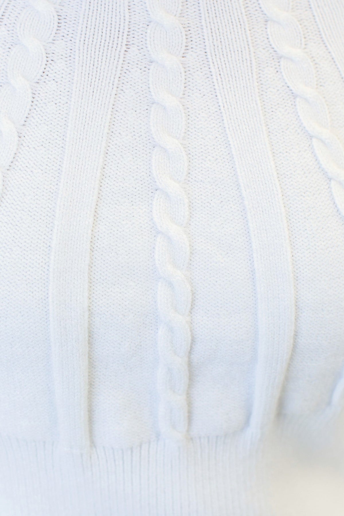 Close-up of the white Alma Jumper showcasing the cable knit design and round neckline.