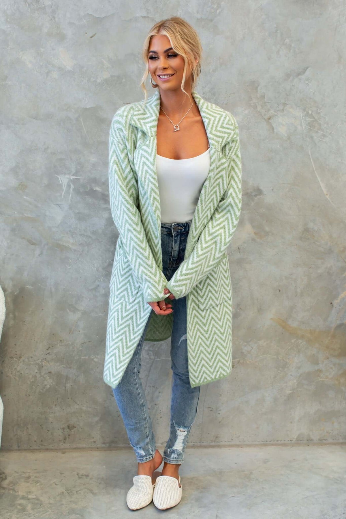 Model wearing Adabella Cardigan, a longline knit cardigan with a zigzag pattern, paired with jeans and slip-on shoes.