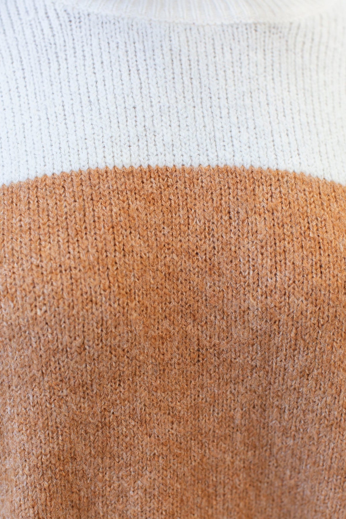 Close-up of Wezen jumper showing soft knit fabric in white and tan color block design, highlighting texture and quality.