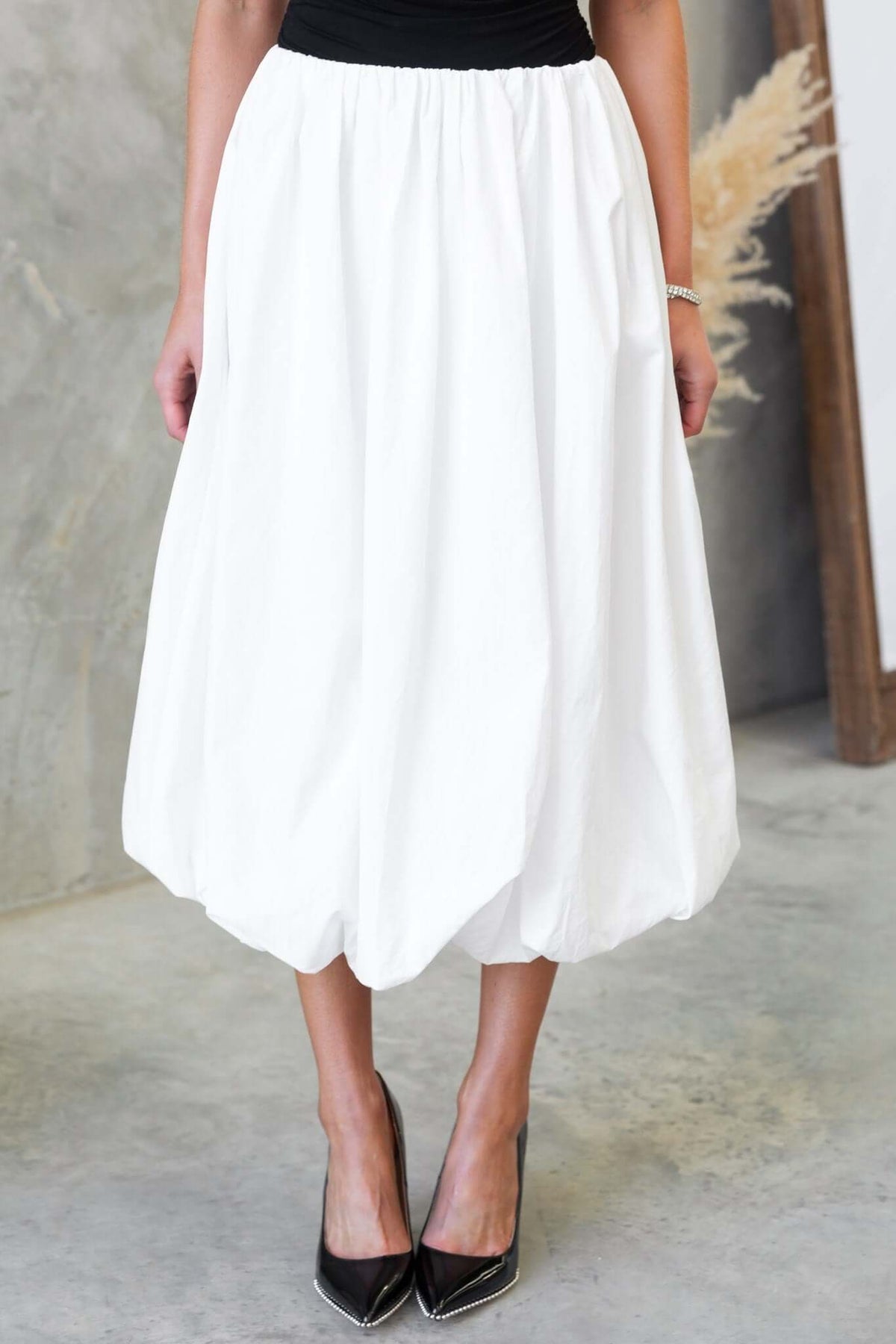 Model wearing the Cloud Nine Midi Skirt, a white mid-high waist cotton skirt with an elastic waistband.