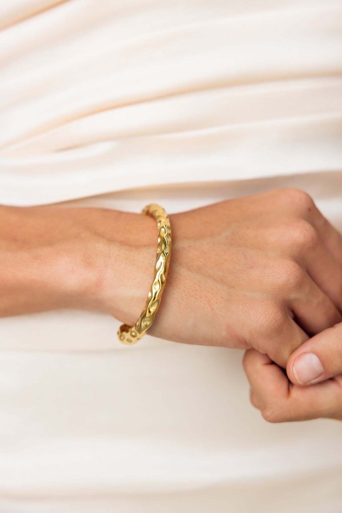 Ever After Bracelet: Textured gold open cuff style bracelet worn on a wrist, showcasing its intricate design and elegance.