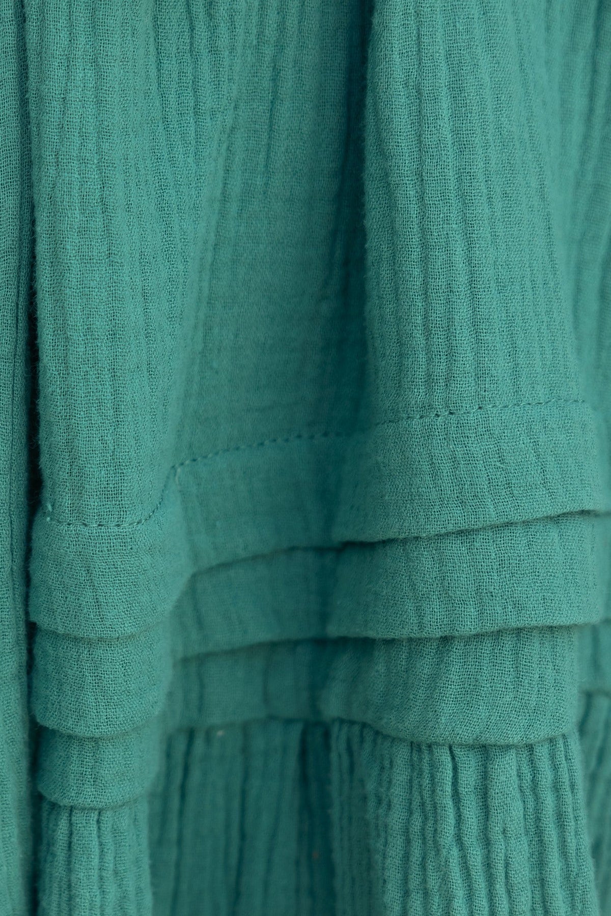 Close-up of textured green fabric from the Hejda Dress, showcasing its lightweight, breathable cotton material.
