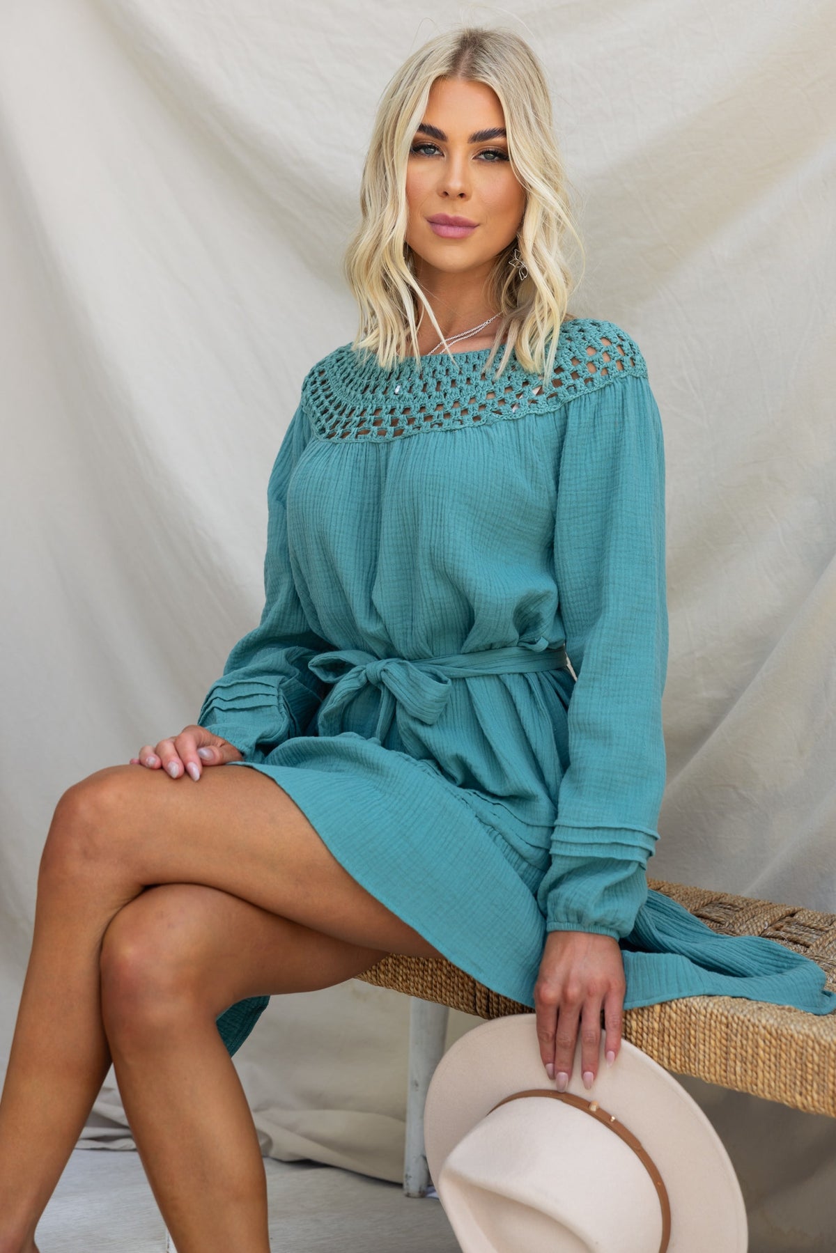 Model wearing Hejda Dress featuring a crocheted boat neckline and removable tie, styled with a hat.