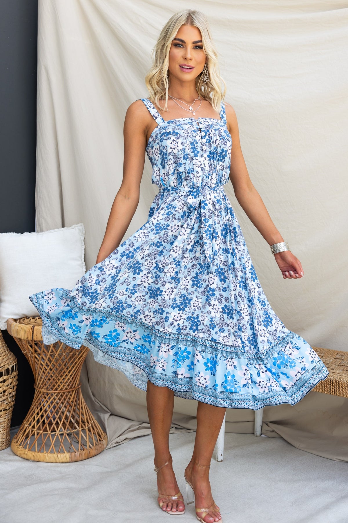 Model wearing Sevila Midi Dress with floral pattern, adjustable straps, and removable tie, styled for a summer look.