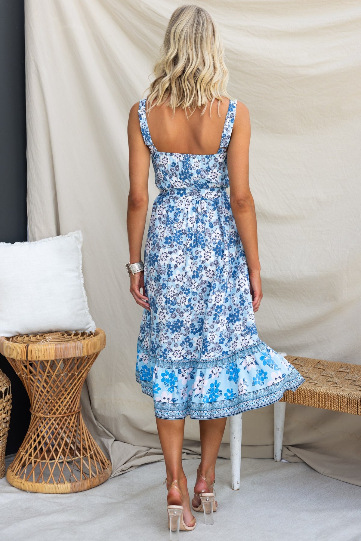 Back view of the Sevila Midi Dress with floral pattern, adjustable straps, and layered hem, styled with chic accessories.